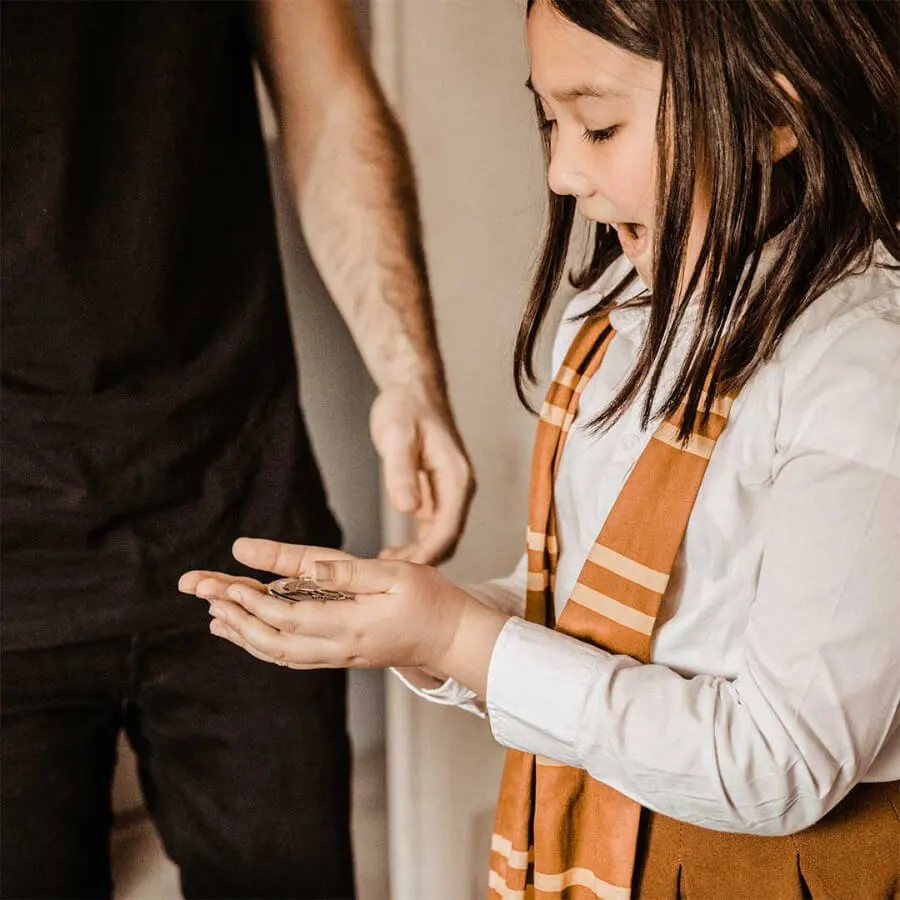 une enfant est émerveillée devant un tour de magie avec une pièce
